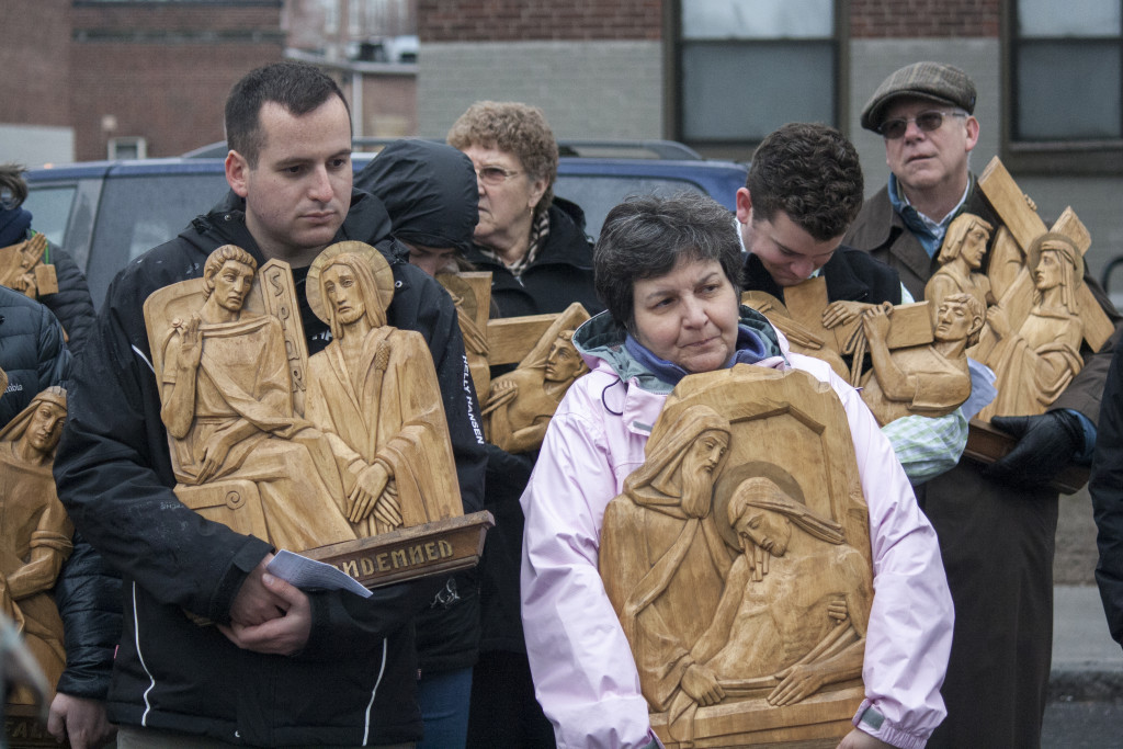 Participants in the outdoor ecumenical Way of the Cross hold some of the 14 depictions of the Stations of the Cross, which were later returned to St. Monica Church, on Friday, March 25, 2016. (Photo by Susan Doucet)