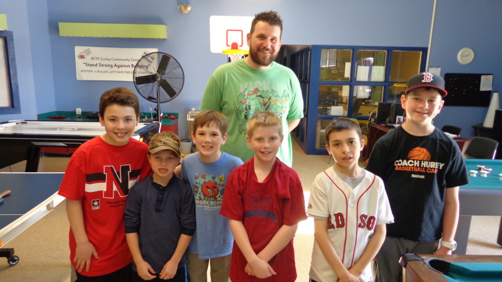Shawn McDonagh stands with Curley Community Center kids (from left) James, Michael, Andrew, Mullen, Dillon, and Brendan on Thursday. That day, the youngsters were busy outside in the beach playing pick-up baseball or watched the Red Sox game on TV. McDonagh cooked hot dogs and supplied drinks for the youngsters courtesy of the Curley Community Center. (Photo by Kevin Devlin)