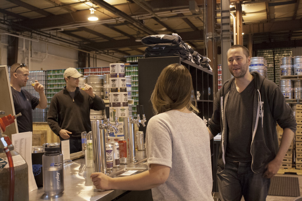Tasting and retail staff assist customers at Castle Island Brewing Company in Norwood on Thursday, March 31, 2016. (Photo by Susan Doucet)